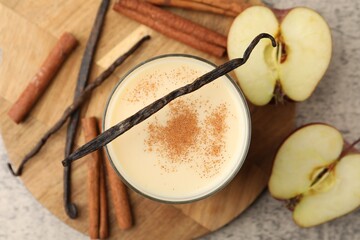 Delicious protein shake in glass, apples, cinnamon and vanilla pods on grey table, top view
