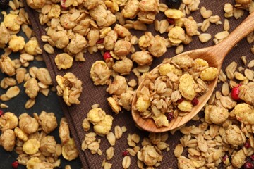 Tasty granola with dried fruits and spoon on black table, top view