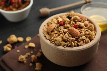 Tasty granola with dried fruits, nuts and honey on black table, closeup. Space for text