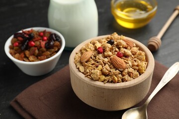 Tasty granola with dried fruits, nuts, honey and milk on black table, closeup