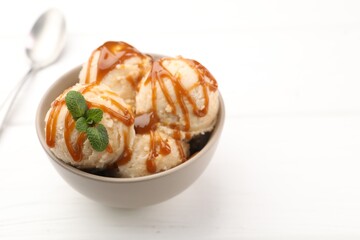 Tasty ice cream with caramel sauce and mint on white table, closeup. Space for text