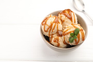 Tasty ice cream with caramel sauce and mint on white table, closeup. Space for text