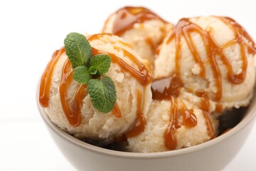 Tasty ice cream with caramel sauce and mint on white table, closeup