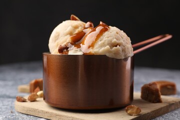 Tasty ice cream with caramel sauce and almonds on grey table, closeup