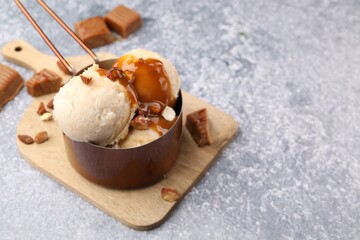 Tasty ice cream with caramel sauce and almonds on grey table, closeup. Space for text