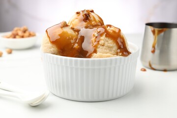 Tasty ice cream with caramel sauce and almonds on white table, closeup