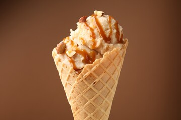 Tasty ice cream with caramel sauce and almonds on brown background