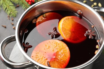Tasty mulled wine in pot on black table, closeup
