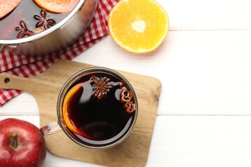 Mug with tasty mulled wine and ingredients on white wooden table, flat lay. Space for text