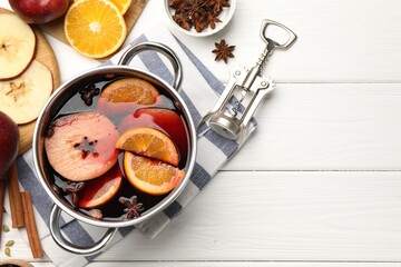 Tasty mulled wine in pot, ingredients and corkscrew on white wooden table, flat lay. Space for text