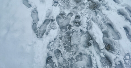 Footprints in snow create an artistic pattern on a winter trail, showcasing trails and ice textures in a cold outdoor environment. Ideal for nature-related projects.