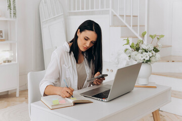 Independent woman at workstation, Female freelancer organizing her daily schedule and goals at desk, Independent woman multitasking with technology and planning tools in serene home office setting