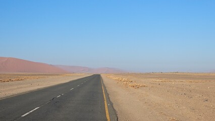 Long straight road disappearing into the desert horizon in Namibia. Symbol of direction, future, opportunity and exploration. Clean minimal travel landscape with wide open space
