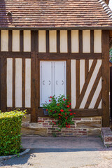 A small house with a window and a potted plant in city Camembert France Normandy. The house is old and has a rustic feel