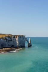 A beautiful blue ocean with a cliff in the background in Etretat France Normandy The cliff is a part of a larger rock formation The shape of the stone arch resembles an elephant's trunk