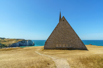 A church Chapelle Notre Dame de la Garde on a cliff overlooking the ocean in Normandy, France Stones of the stage are visible in the background