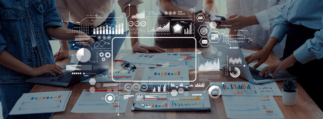 A diverse team engages in a collaborative marketing strategy session using data analytics tools, surrounded by charts, graphs, and laptops in a modern office environment. Trope