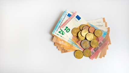 Euro banknotes and coins on white background with copy space.