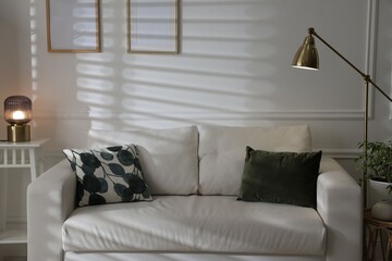 Comfortable sofa, lamps and houseplant indoors. Interior design