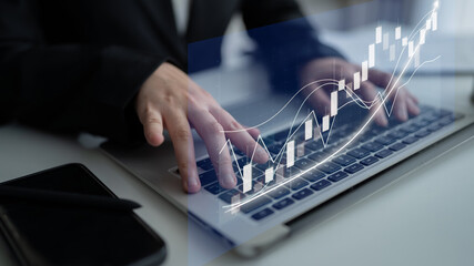 A business professional interacts with a laptop, analyzing financial data represented by an overlay of charts and graphs in a modern office setup. Impute