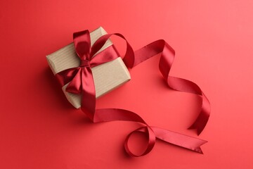 Gift box with beautiful ribbon on red background, top view