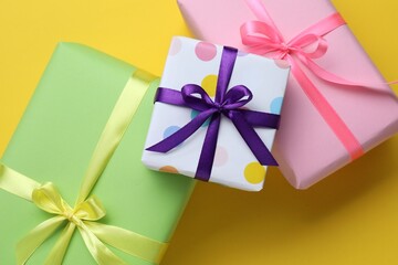 Beautiful wrapped gifts on yellow background, flat lay