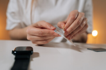 Person preparing screen protector for smartwatch, ensuring device care and maintenance, protecting technology from scratches and daily wear, extending gadget lifespan.