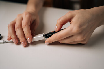 Woman connecting adapter to cable sitting at white table, preparing electronic devices for charging...