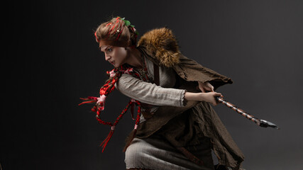 Nordic warrior woman in natural dress holding axe, fur cape on gray background. axe blow