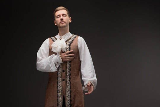 A young man in a theatrical costume in the style of Shakespeare's plays, photo on a gray background. Historical costume, Renaissance or Baroque character