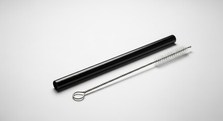 Fototapeta premium Black metal reusable straw with cleaning brush laid on white background sustainable drinkware eco conscious lifestyle