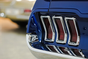 Tail light and bumper close-up details of a blue vintage American Car. Rear view of a classic car with copy space.