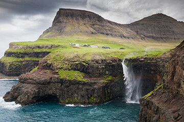 waterfall with the village Gasadalur in background on faroe islands