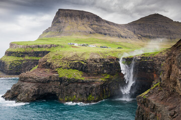 waterfall with the village Gasadalur in background on faroe islands