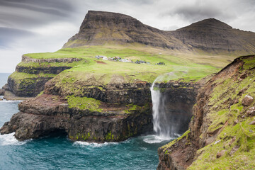 waterfall with the village Gasadalur in background on faroe islands