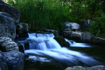Fototapeta premium Cascading Waterfall Through Forest with Bamboo and Rocks