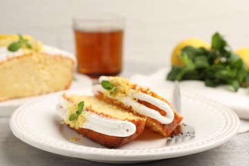 Delicious lemon cake with glaze, fresh fruit slices and mint served on table, closeup