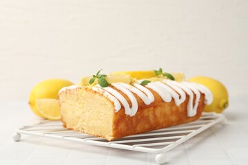 Delicious lemon cake with glaze, fresh fruit slices and mint on light table, closeup