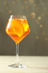 Refreshing spritzer cocktail on light table against grey background with bokeh effect