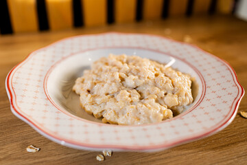 Creamy oatmeal on a patterned plate, styled on a wooden table with warm lighting for a cozy, homemade breakfast feel.