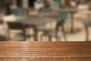 Empty wooden table against blurred view of tables and chairs in cafe. Space for design