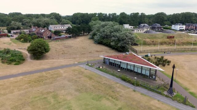 Aerial view of semi rural town with green roofed modern building, black monument, and FORT 1881 sign blending contemporary design with historical and natural surroundings.