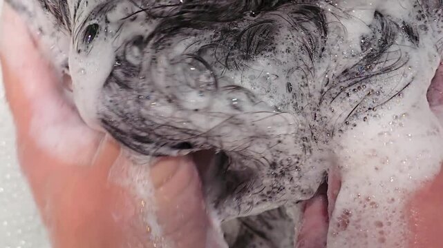 professional scalp massage and hair washing with rich foam in a beauty salon. Spa treatment concept. hairstylist spa therapist massages and washes long dark hair, using shampoo and peeling mask