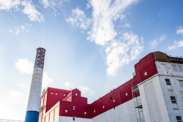 Patriotic red, white, and blue industrial building painted in American flag colors with star-decorated smokestack under blue sky