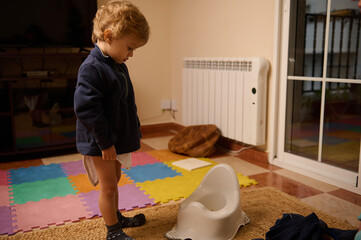 Little Child Stands Beside Potty Training Chair in Colorful Playroom at Home