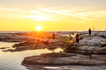 Friends explore the unique rock formations of Georgian Bay Ontario in the golden light of the setting sun while on a sea kayak expedition room for text