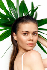 Fototapeta premium Fresh and Radiant Model with Green Leaves, Natural Beauty Concept, Close-Up Portrait, Bright Background