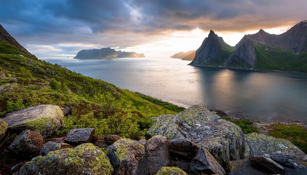 view during midnight sun from husoy toward wonderful oyfjorden senja island norway hiking destination during cloudy summer day on senja island arctic island in norway rocks in foreground fjord