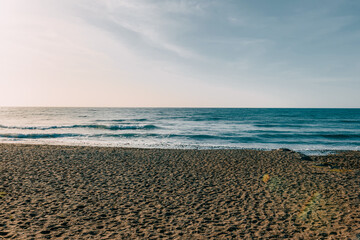 Empty sandy beach on Fuerteventura, Canary Islands, with gentle ocean waves and a wide horizon, minimalist coastal landscape evoking solitude, freedom, travel and winter escape