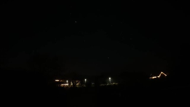 A time-lapse video capturing the moonrise above the night sky, with silhouettes of houses on the horizon. The scene shows a calm, dark atmosphere 